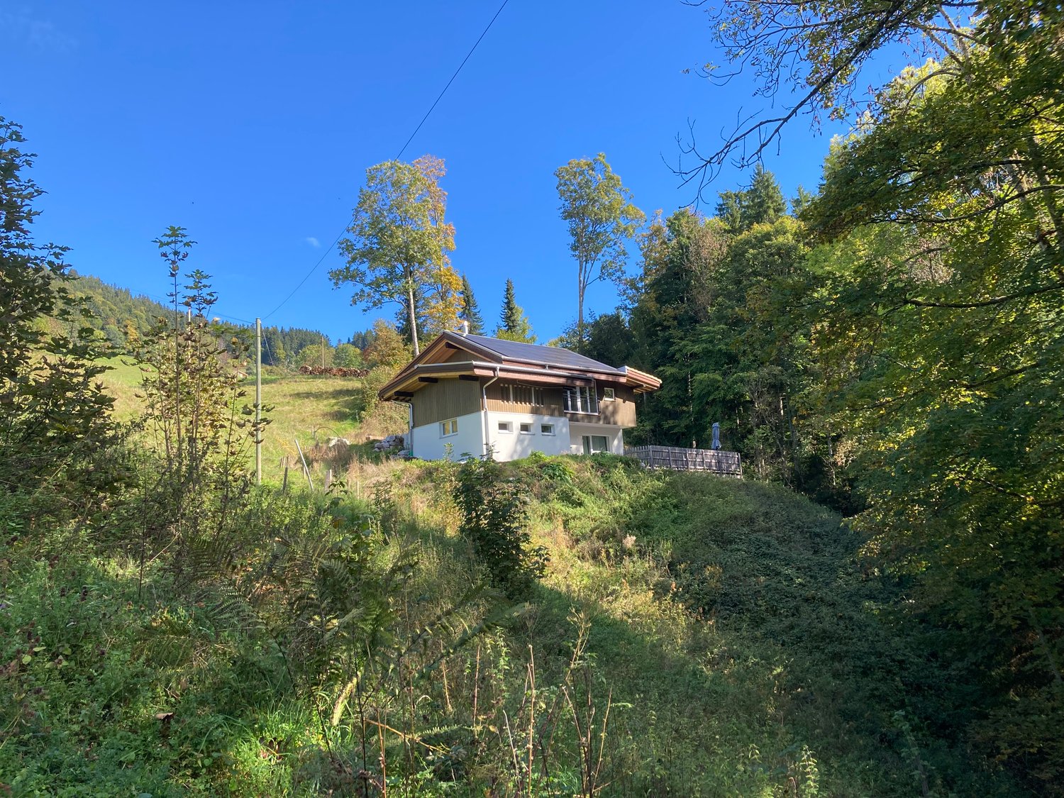 Raised ground floor, white house with brown trim, solar panels, rural setting