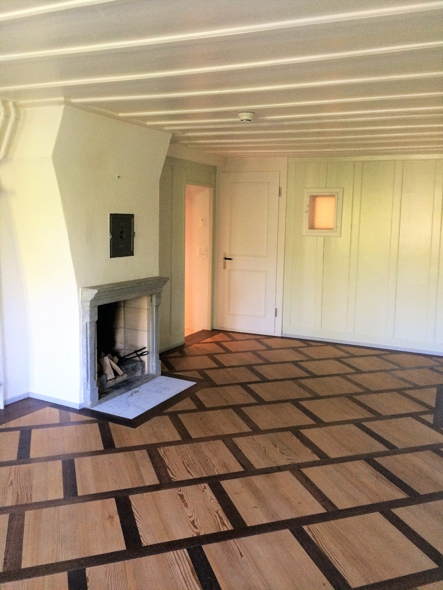 empty room, fireplace, square floor design, white walls, wooden door