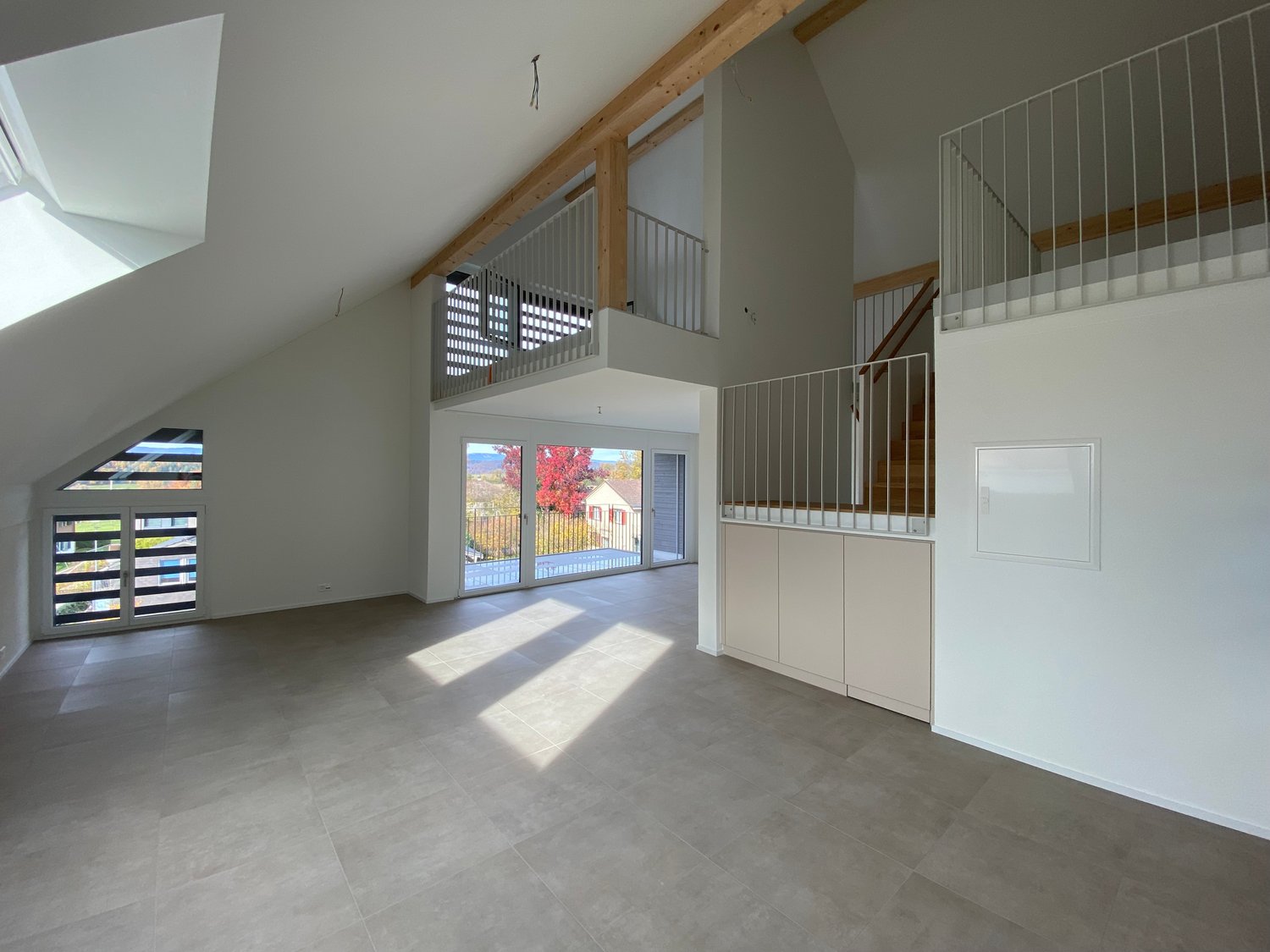large open space, large glass doors, balconies, white walls, tiled floor