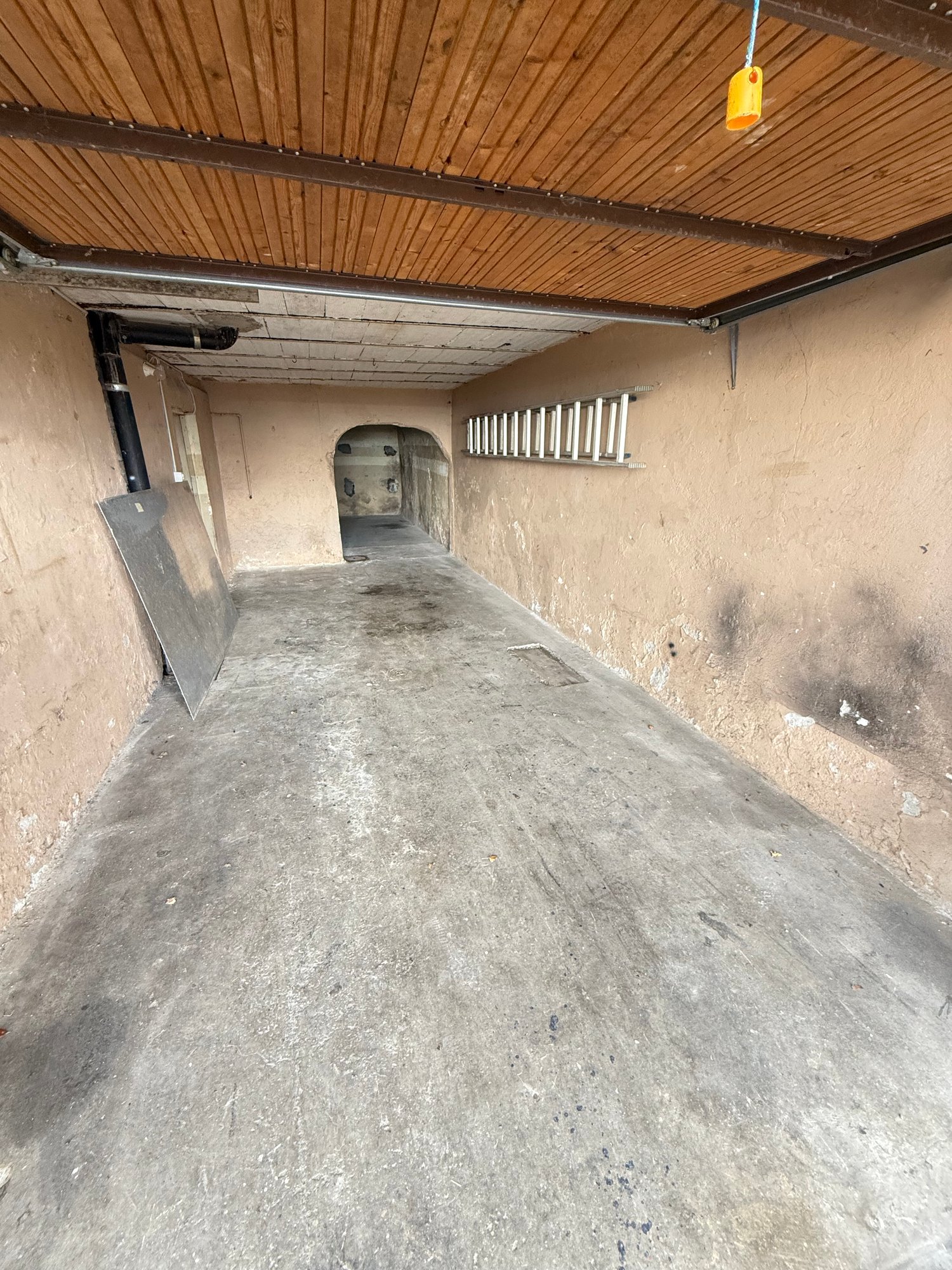 Empty concrete floor, wooden ceiling, ladder on the wall, small hole in the wall
