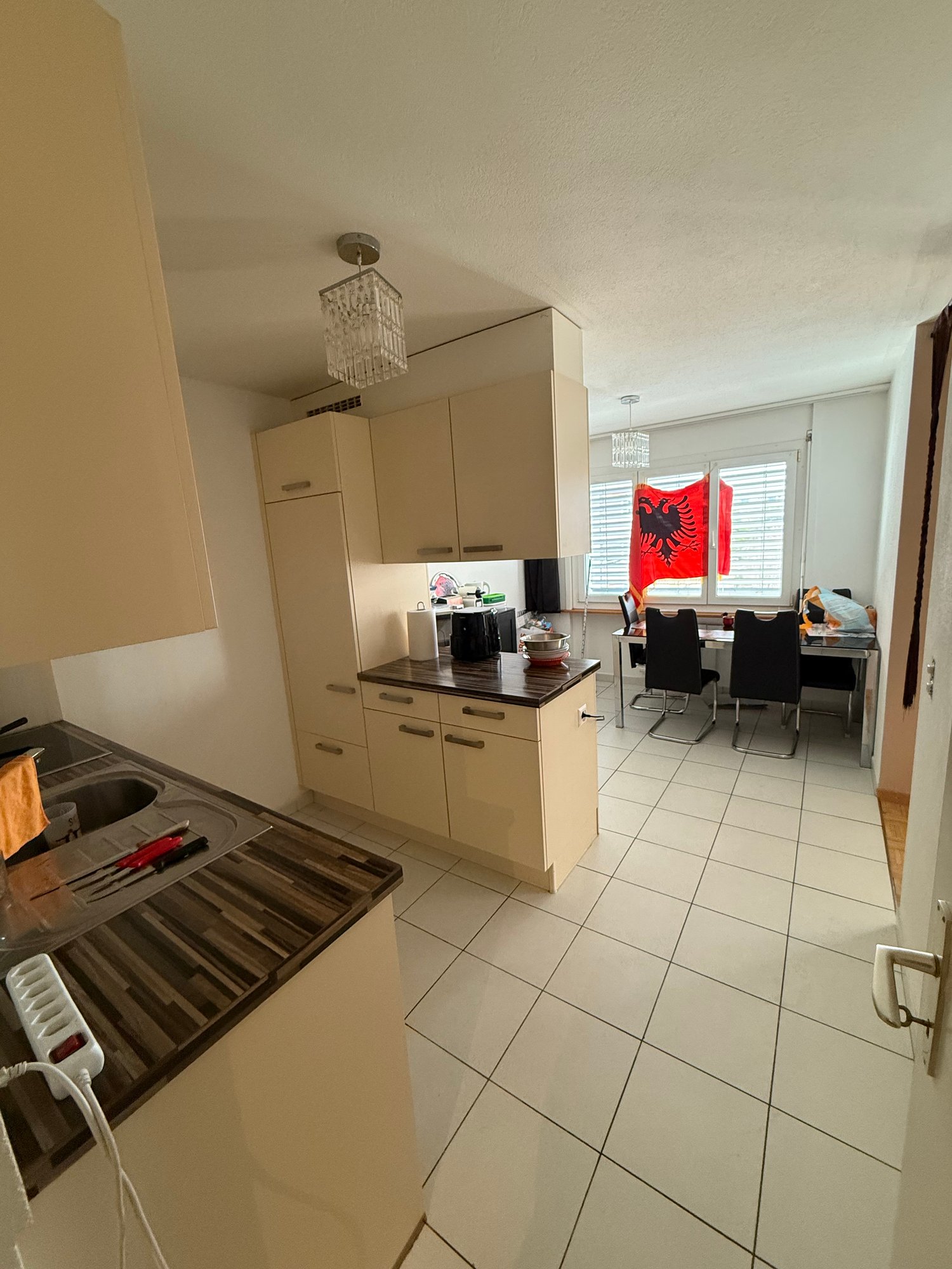 kitchen with dining area, white tiles, wooden countertops, white cabinets, chandelier, dining table, chairs, flags