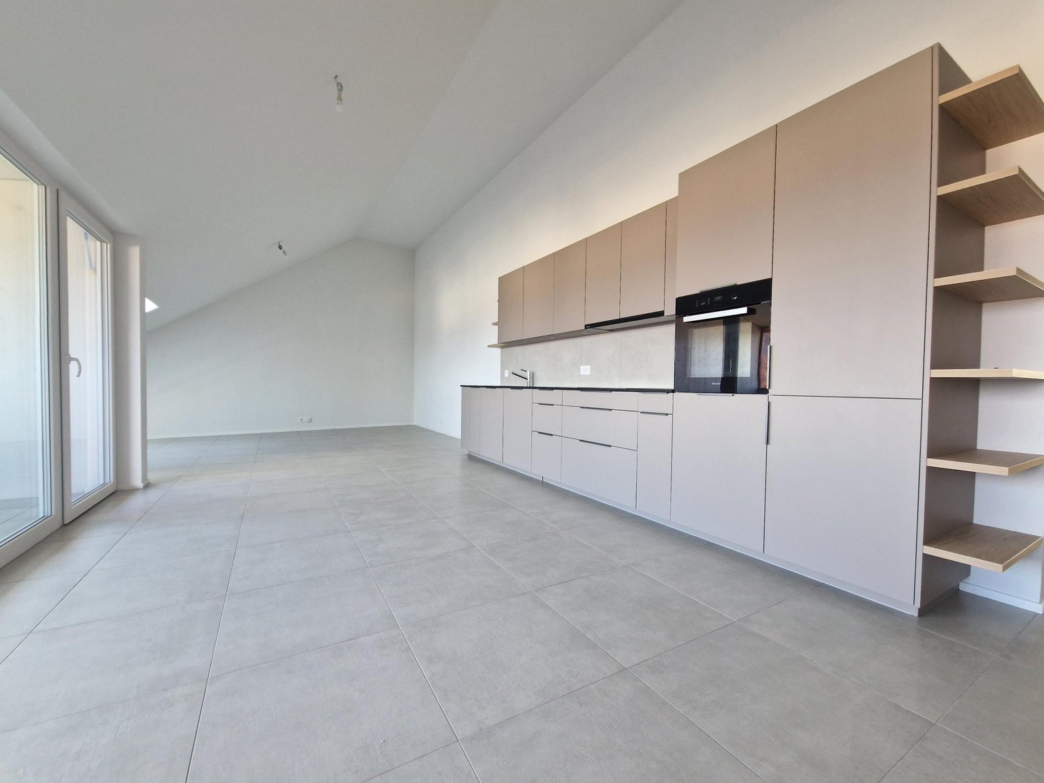 Empty kitchen with tiled floor, white cabinets, built-in oven, sink, and shelves