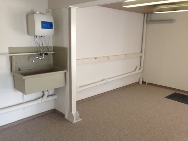 Empty room with a sink, pipes, and a water heater