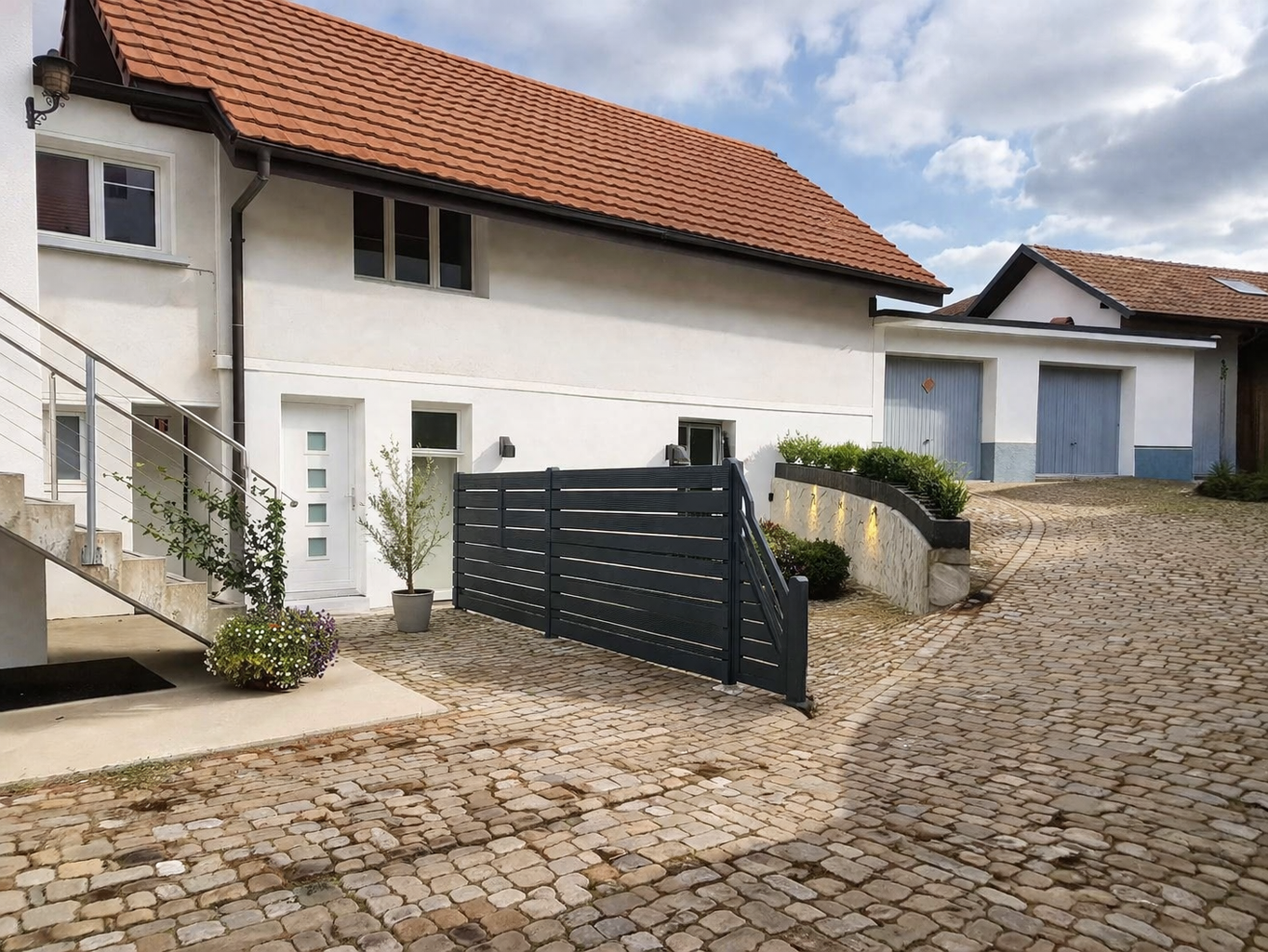 white house, brown roof, black gate, brick driveway, stairs, plants