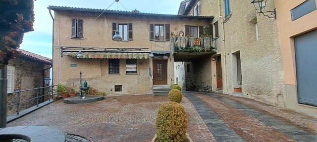 3 story house, beige stone, brown roof, balcony, garden, street lamp, plants