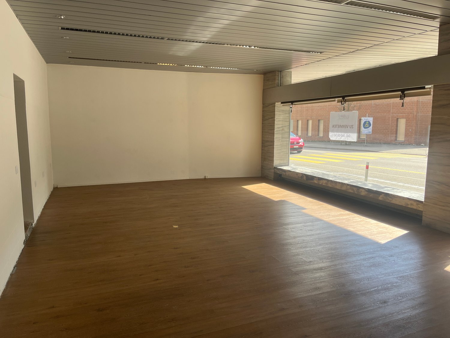 Open room, wooden floor, glass window with a view of a road