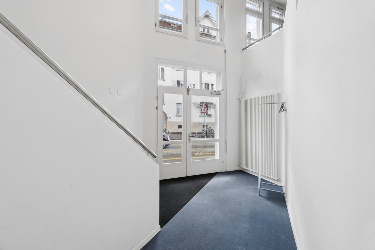 White walls, blue carpet, white radiator, glass doors, metal handrail