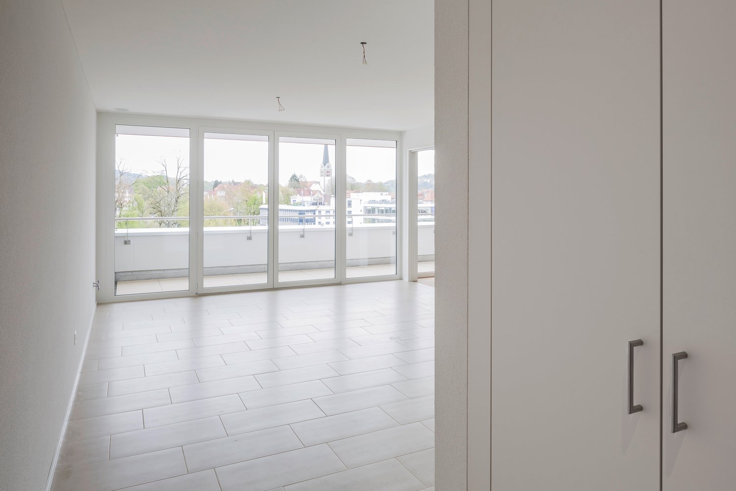 empty room, white tiles, large sliding glass doors, balcony, city view