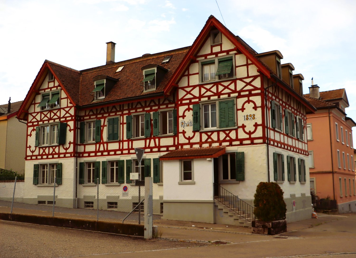 A traditional German half-timbered building with a red tiled roof, green shutters, and decorative wooden beams. The building appears to be a residential or commercial structure, with a sign indicating the year 1898.