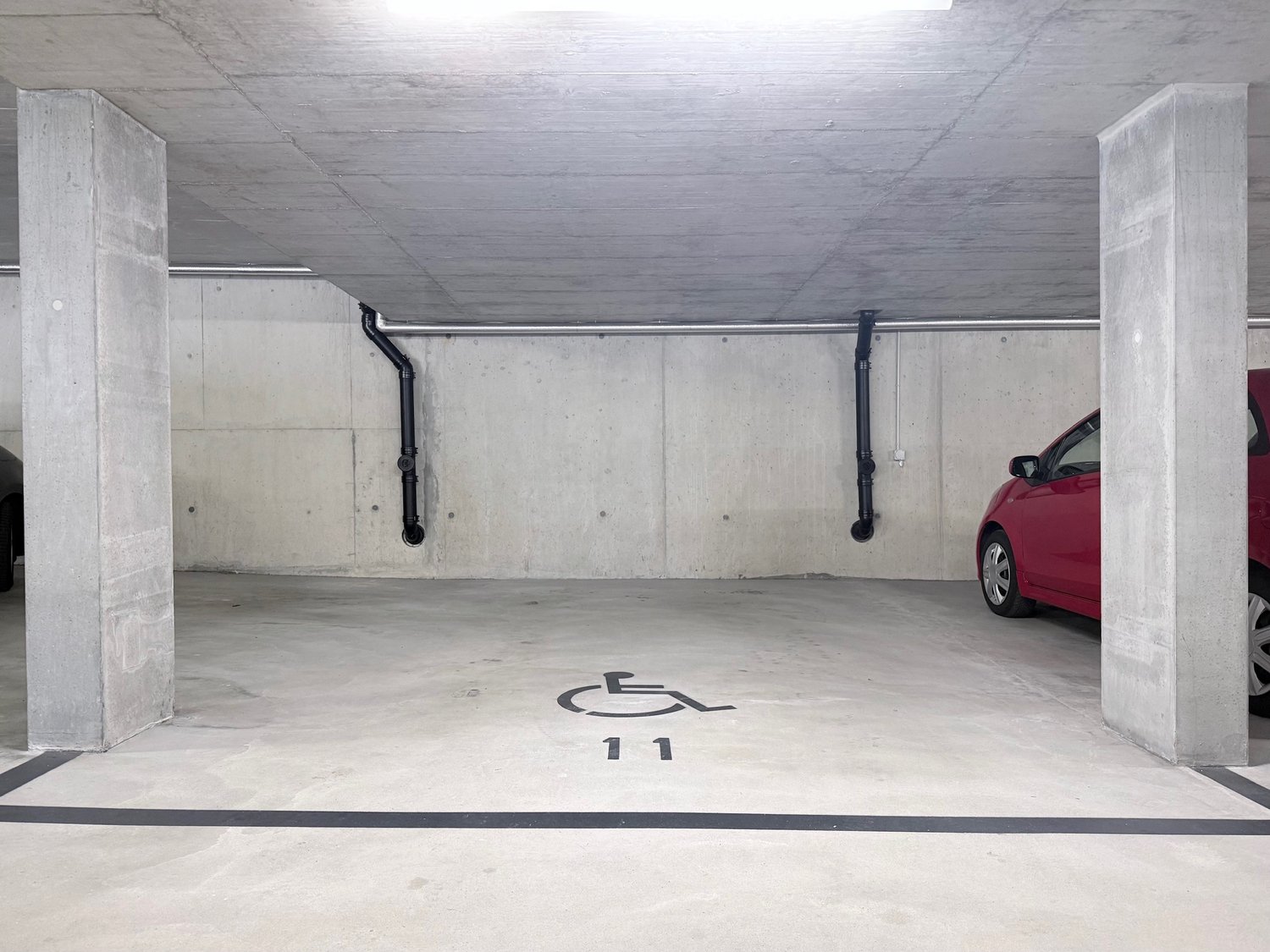 underground parking garage, concrete walls, white floor, designated parking spot number 11