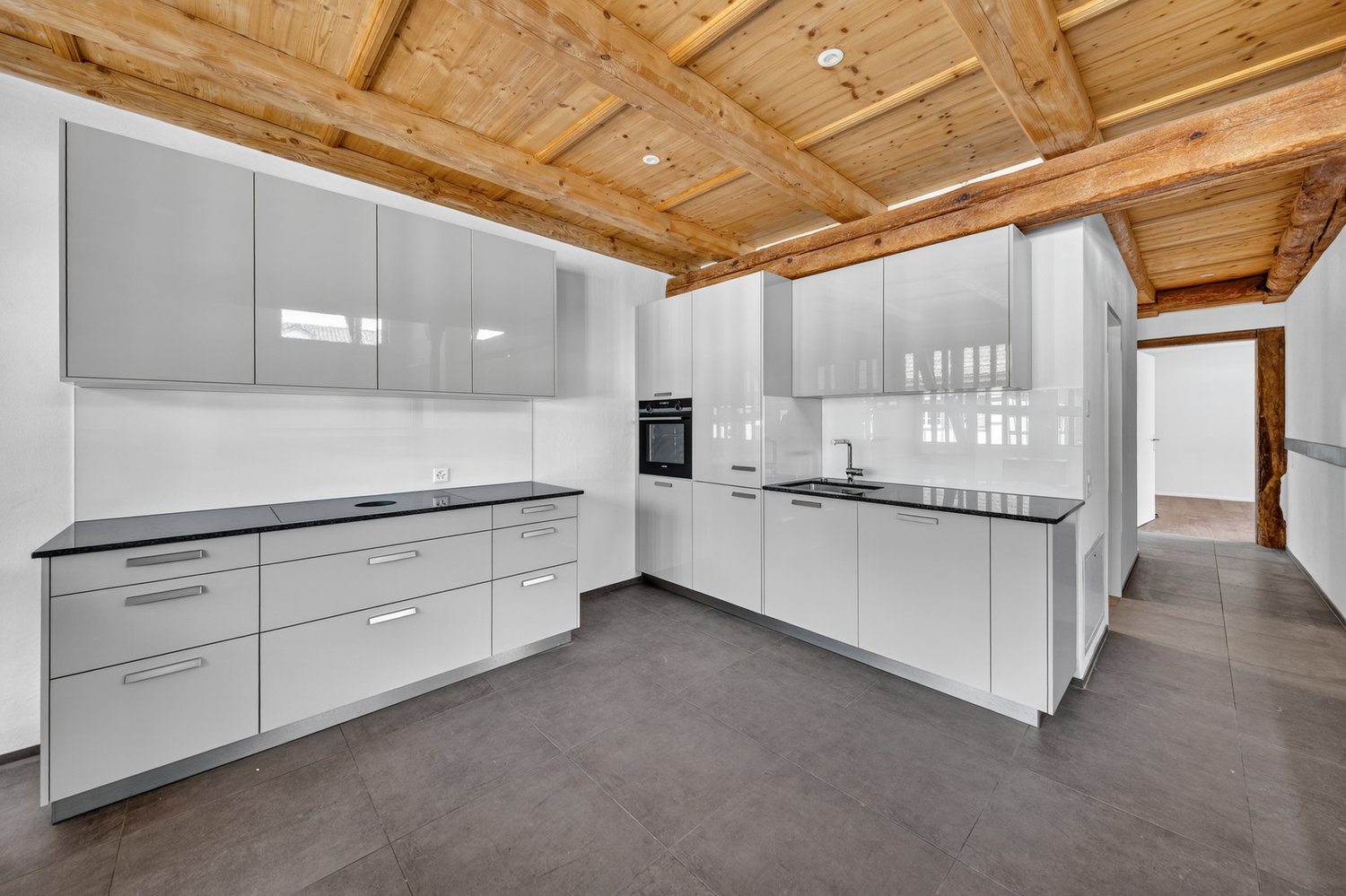 modern kitchen with white cabinets, black countertops, wooden ceiling, built-in oven, sink, faucet, dishwasher, washing machine
