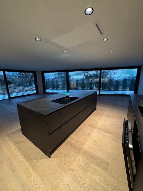 Large central island kitchen, black countertops, large windows, wooden floors