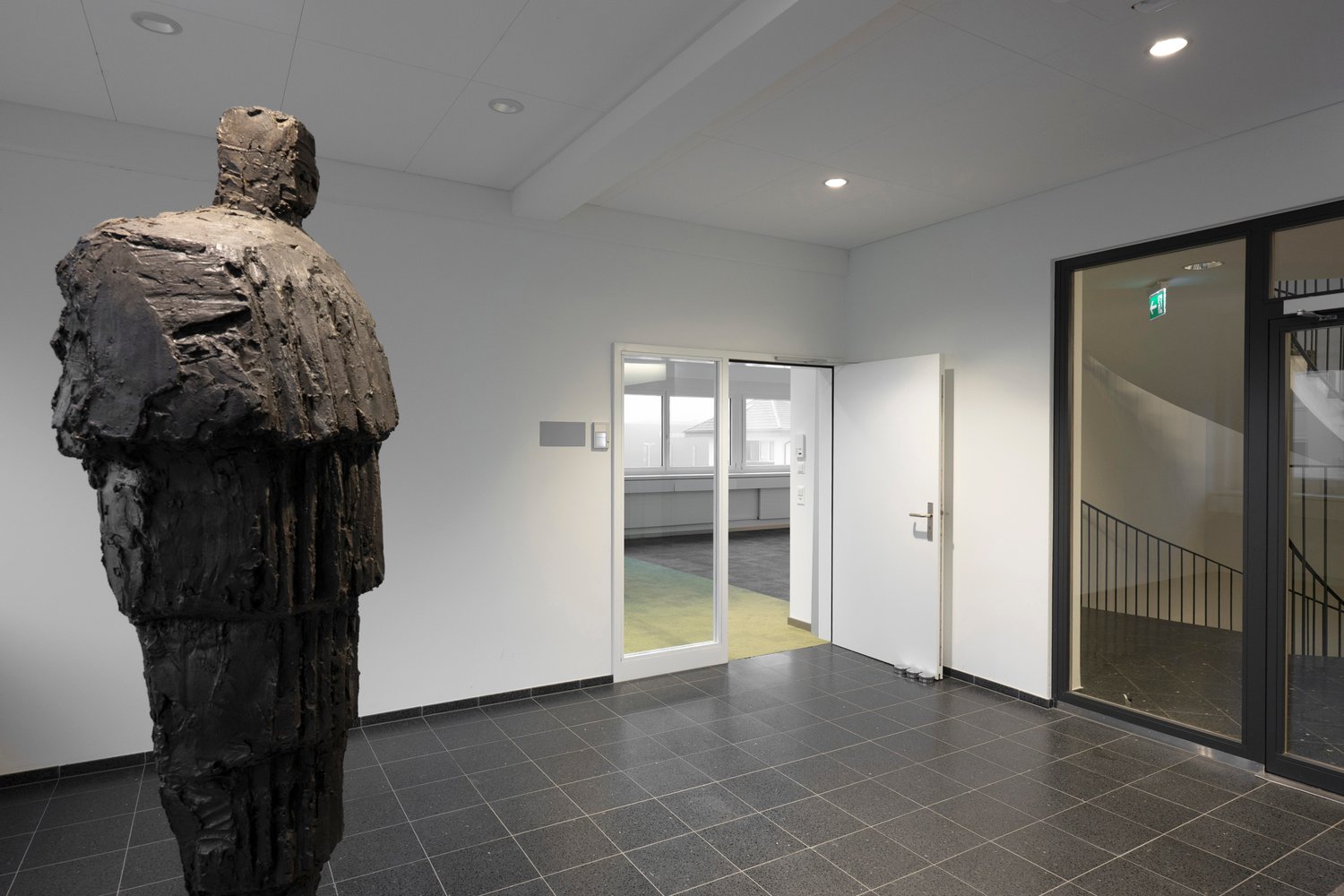 white walls, grey tile floor, open white doors, sculpture