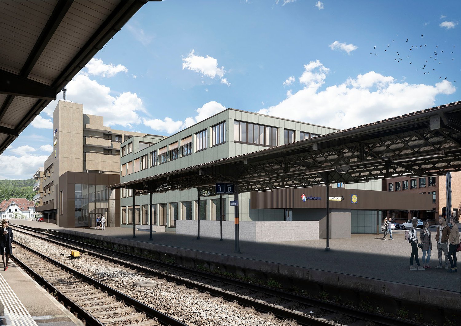 The image shows a modern train station with a covered platform and several buildings surrounding it. The station has a large, open design with glass walls and a metal roof structure. There are people waiting on the platform, and birds can be seen flying o