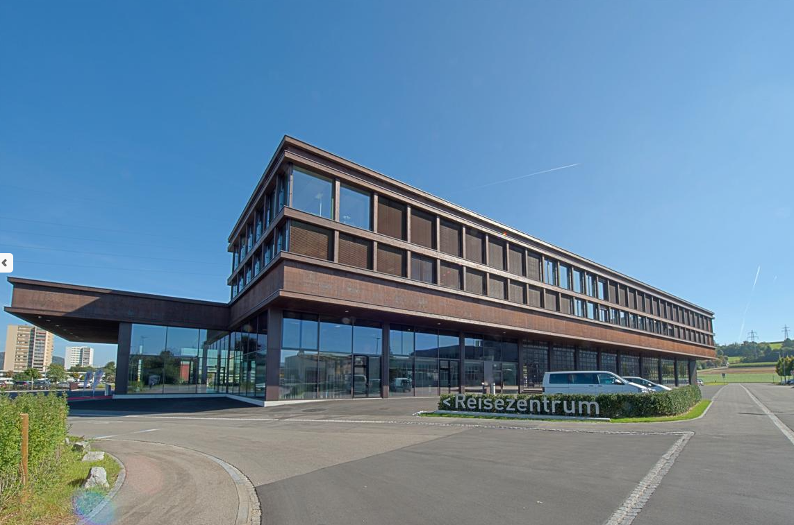 modern office building, large glass facade, brown facade, large parking lot, cars parked in front