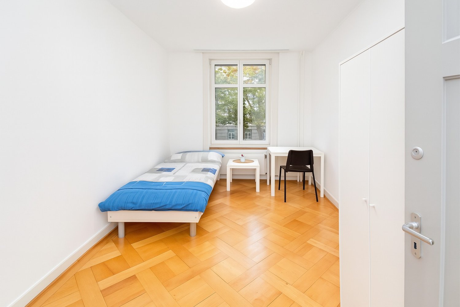 single bed, desk, chair, window, parquet floor