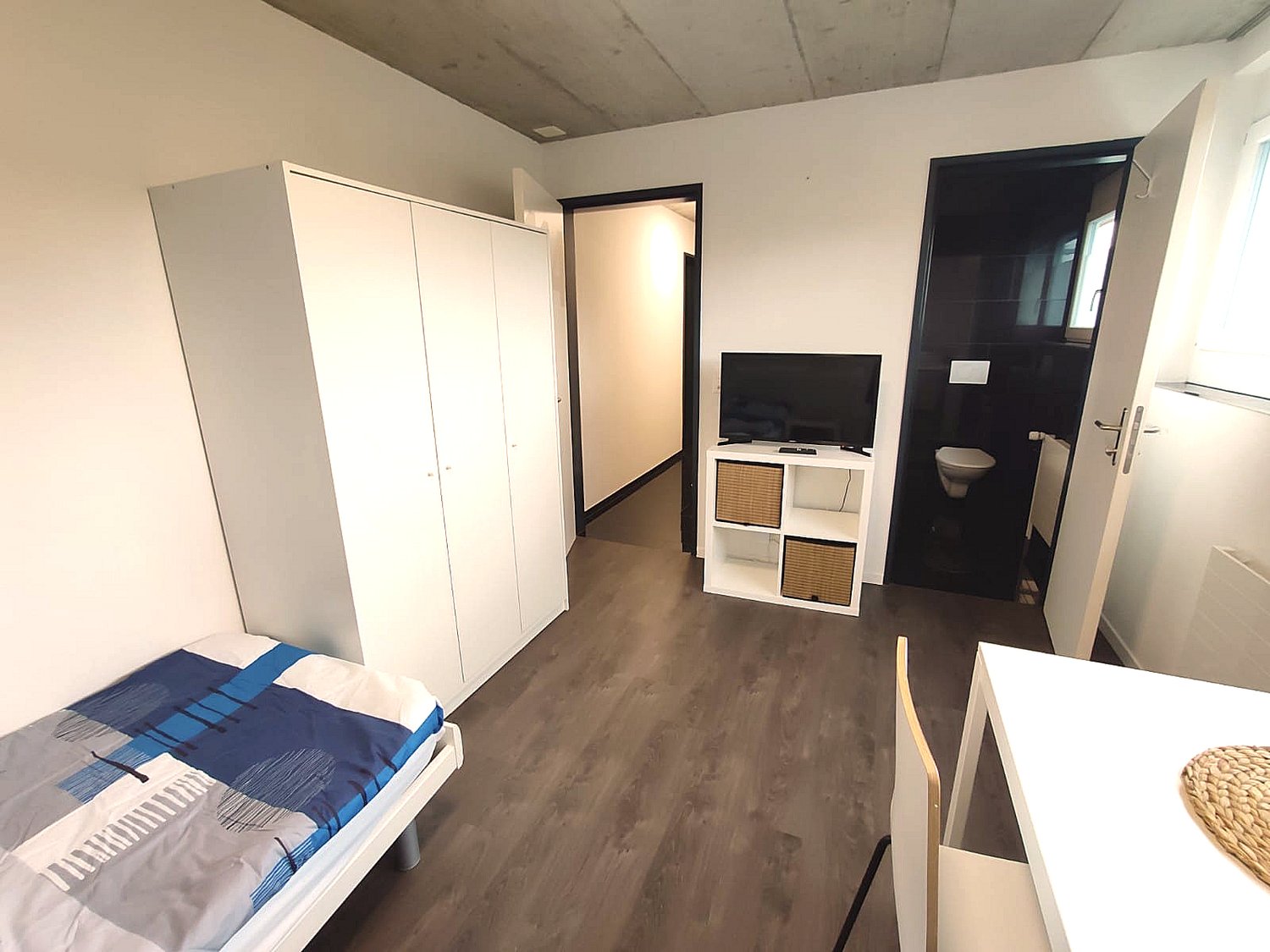 Single bedroom with bed, wardrobe, TV stand, chair, desk, toilet