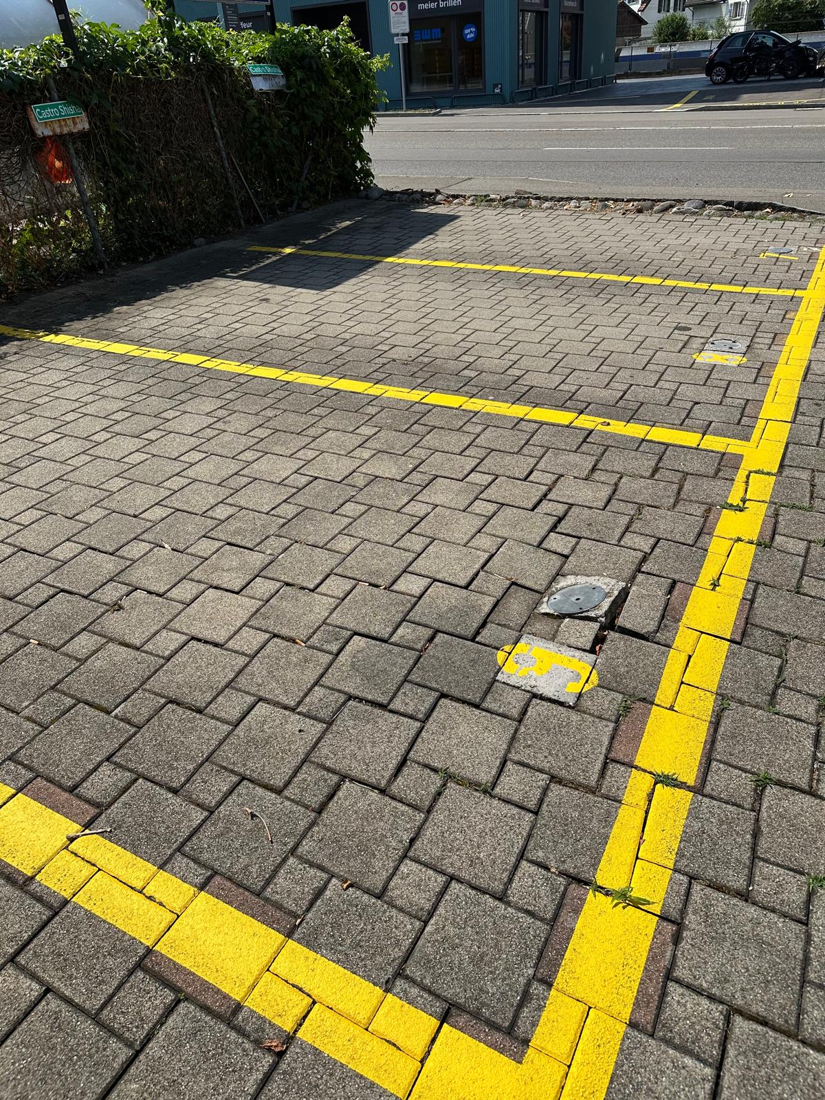A brick paved parking lot with yellow markings