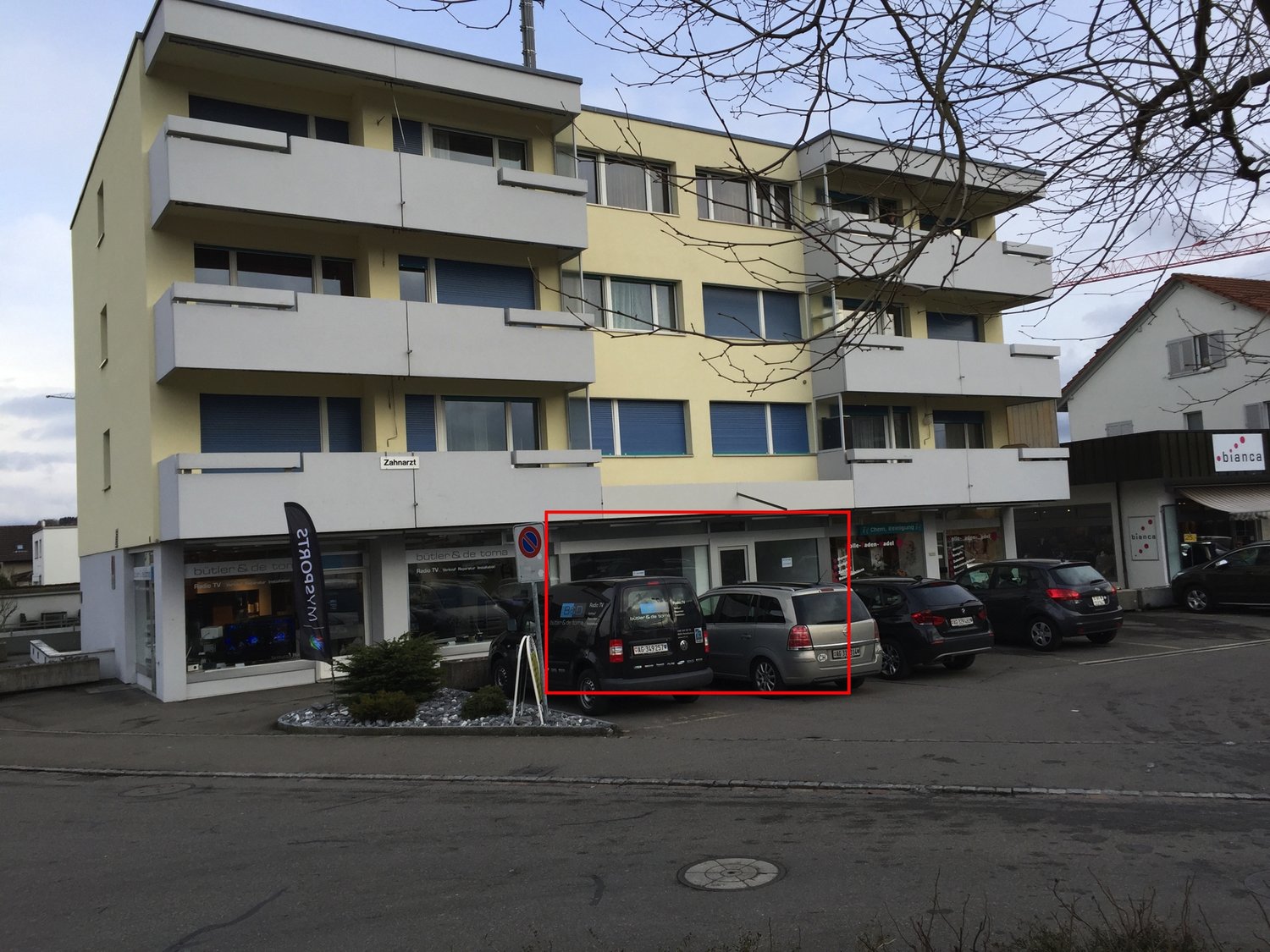 Multi-story building, balconies, yellow exterior, parking lot
