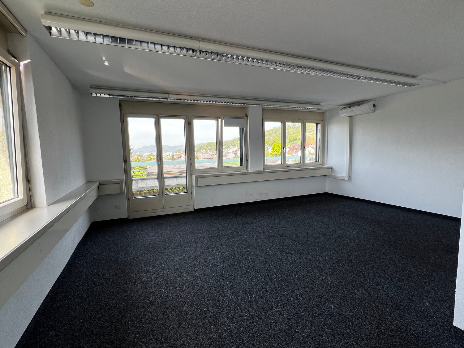 empty room, white walls, black carpet, large windows, air conditioning unit