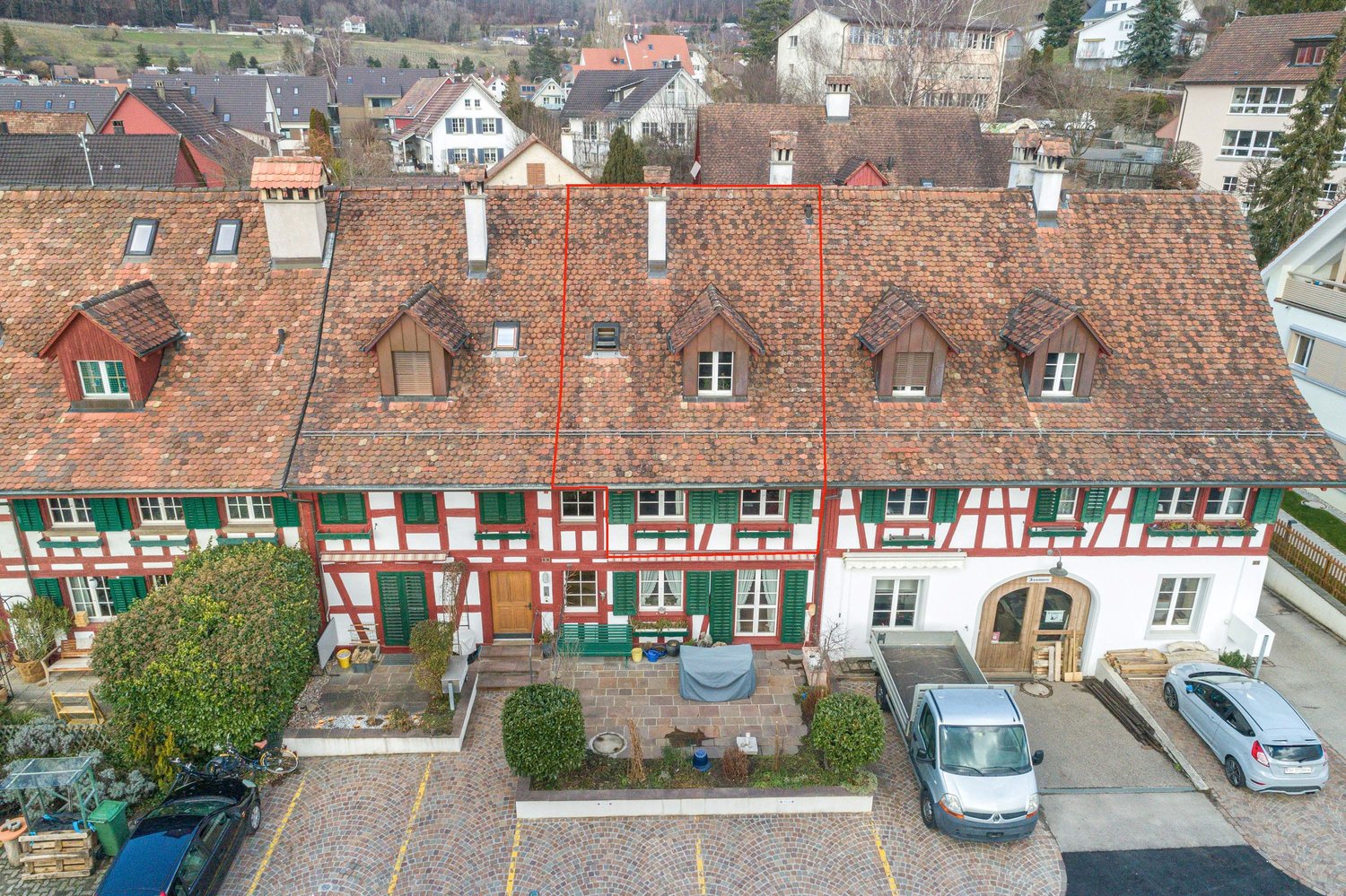 2-story building with red tiled roof, red and white color scheme, green shutters, and a small courtyard in the front