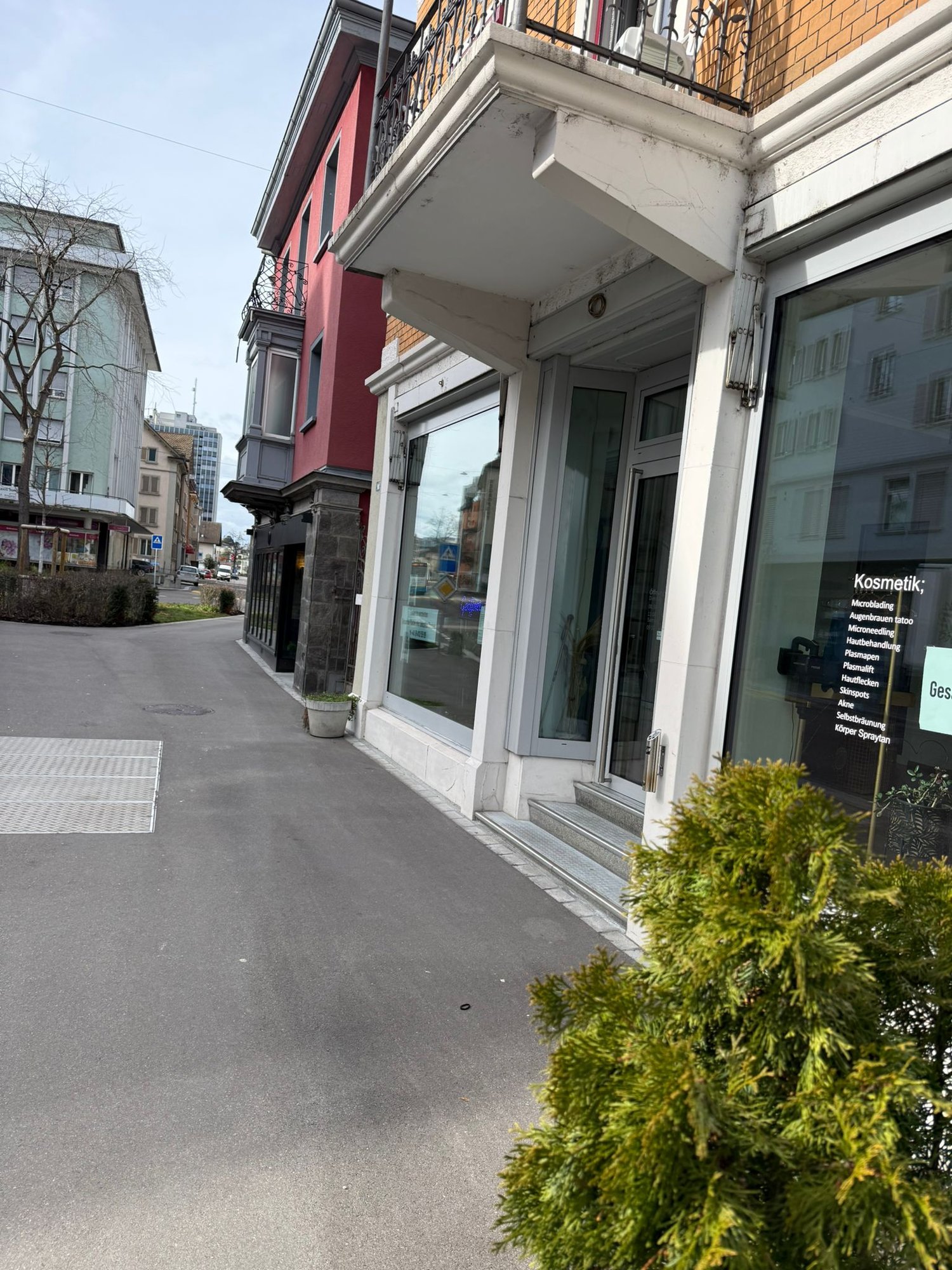 3 story building, brick and white facade, glass door and window, balcony, street sign, parking spot
