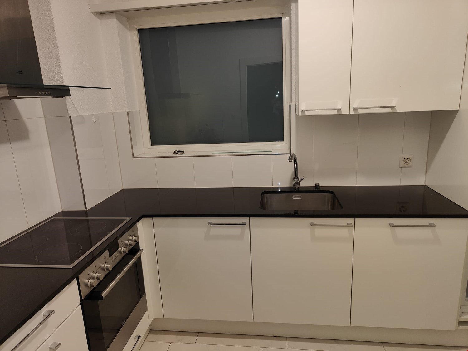 modern kitchen with black counter tops, electric stove, built-in oven, sink, and a window