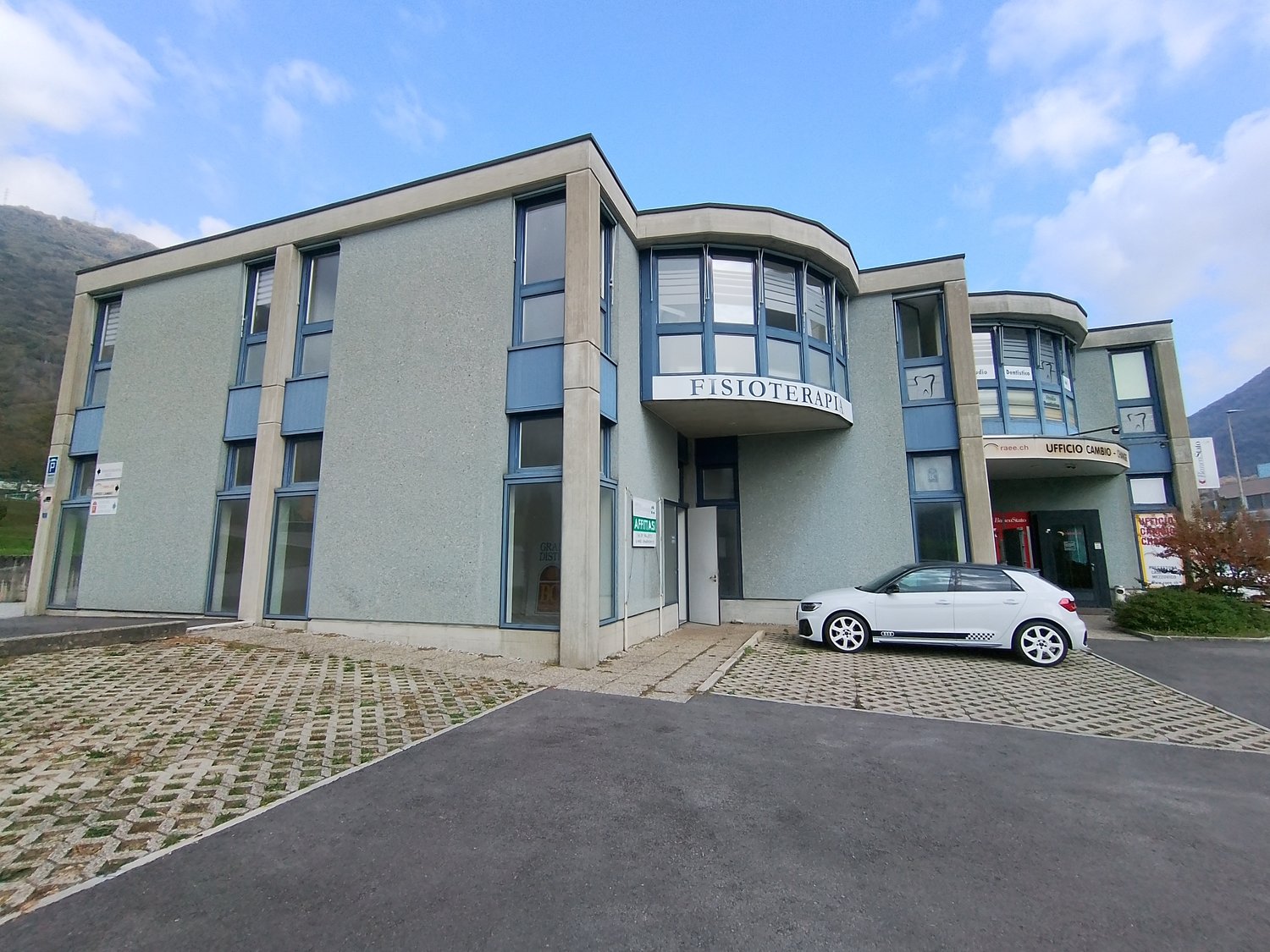 Office building, modern design, glass facade, entrance, small car parked in front