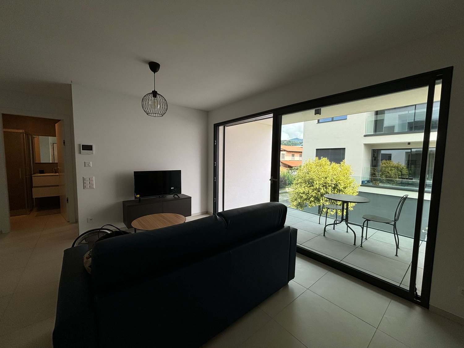 modern apartment, glass wall, couch, flat screen tv, balcony with table and chairs, hardwood floor