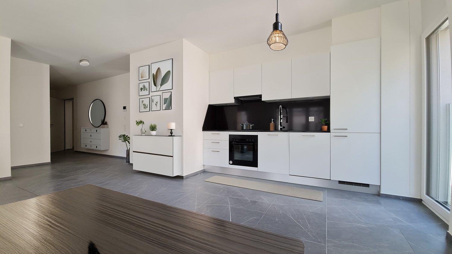 open kitchen with modern furniture, light gray marble flooring, black countertop, oven, dishwasher, several decorative framed pictures on wall