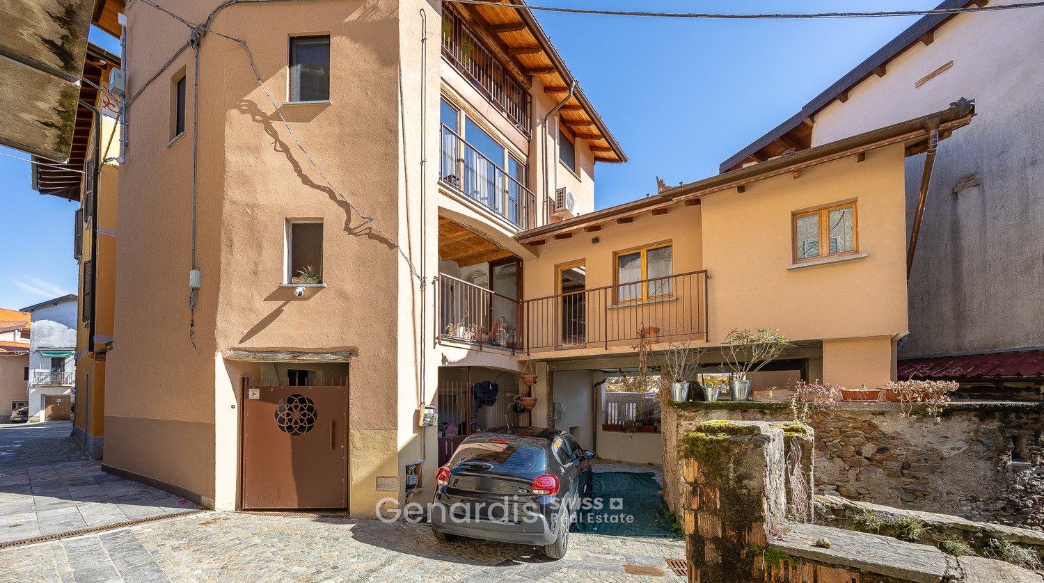 3 story house, beige walls, brown door, balcony, car parked in garage