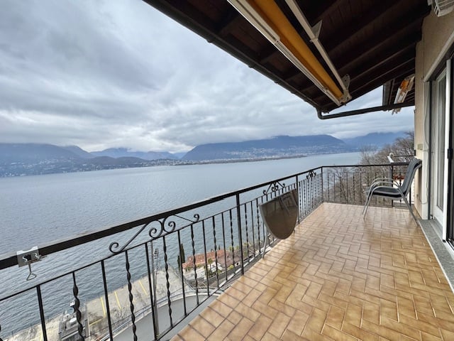 wooden tiled floor, balcony rail, chair, lake view, mountains