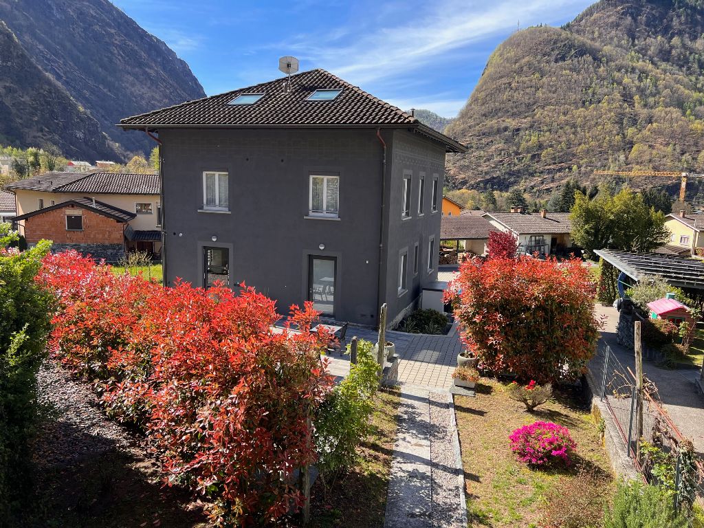 2-story house with a tiled roof, surrounded by colorful autumn foliage and landscaped gardens, set against a backdrop of mountains