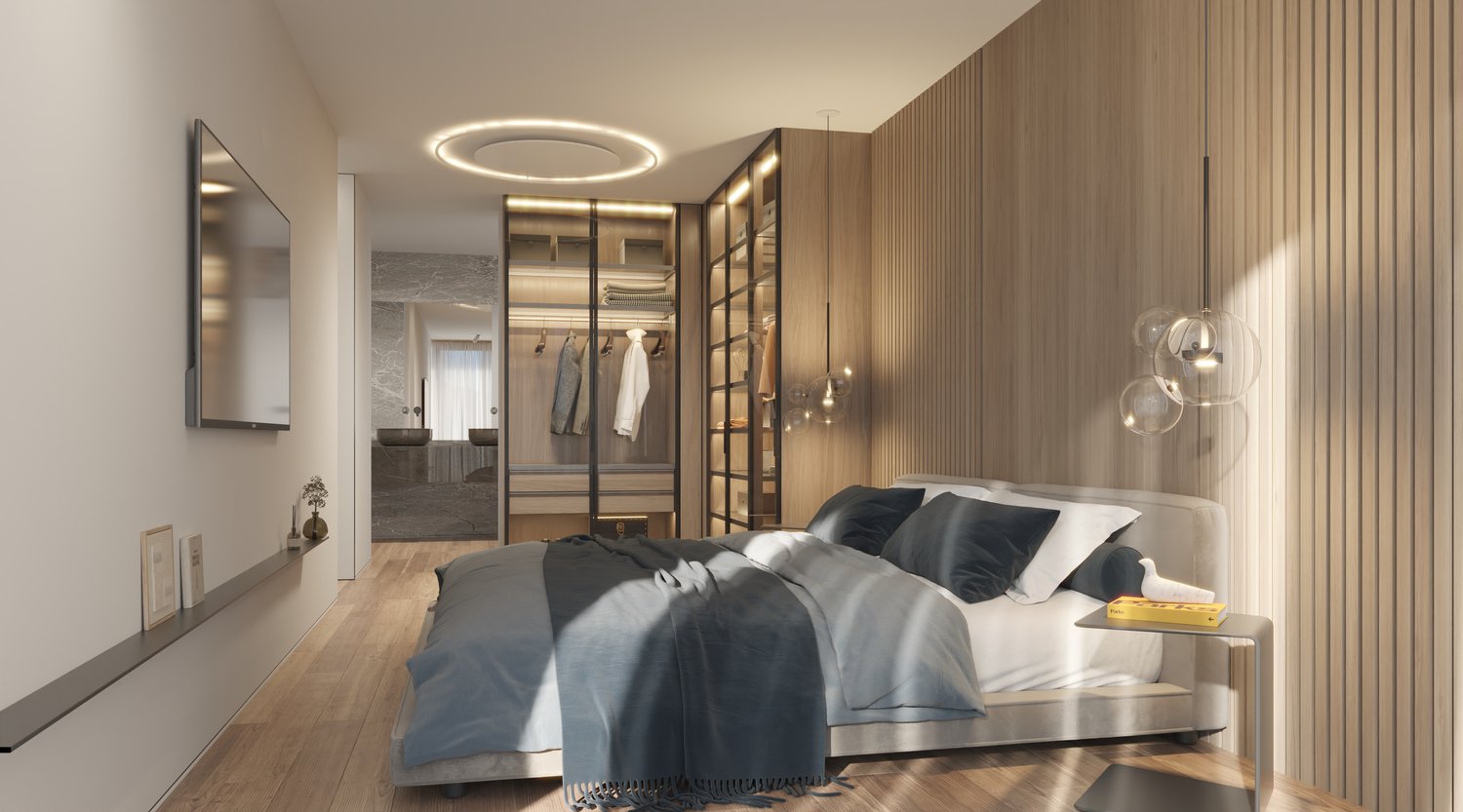 The bedroom features a large bed with a grey duvet and white sheets, and various pillows on it. There is a bedside table with a book and a small plant on a wall-mounted shelf. The room has large windows, and a small cabinet in the corner has clothes hangi