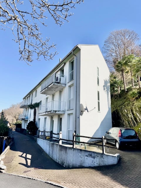 white building, multiple balconies, car parked on the side