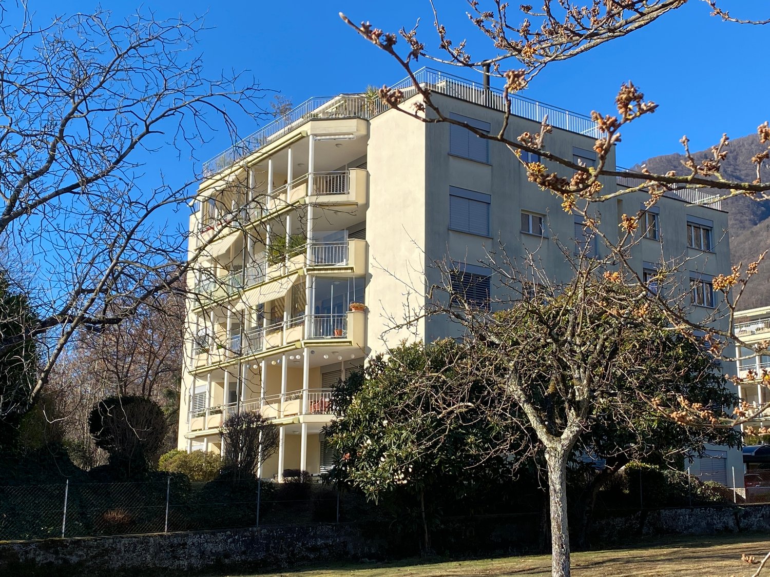 large multistory apartment building with balconies, cream-colored exterior, windows with shutters