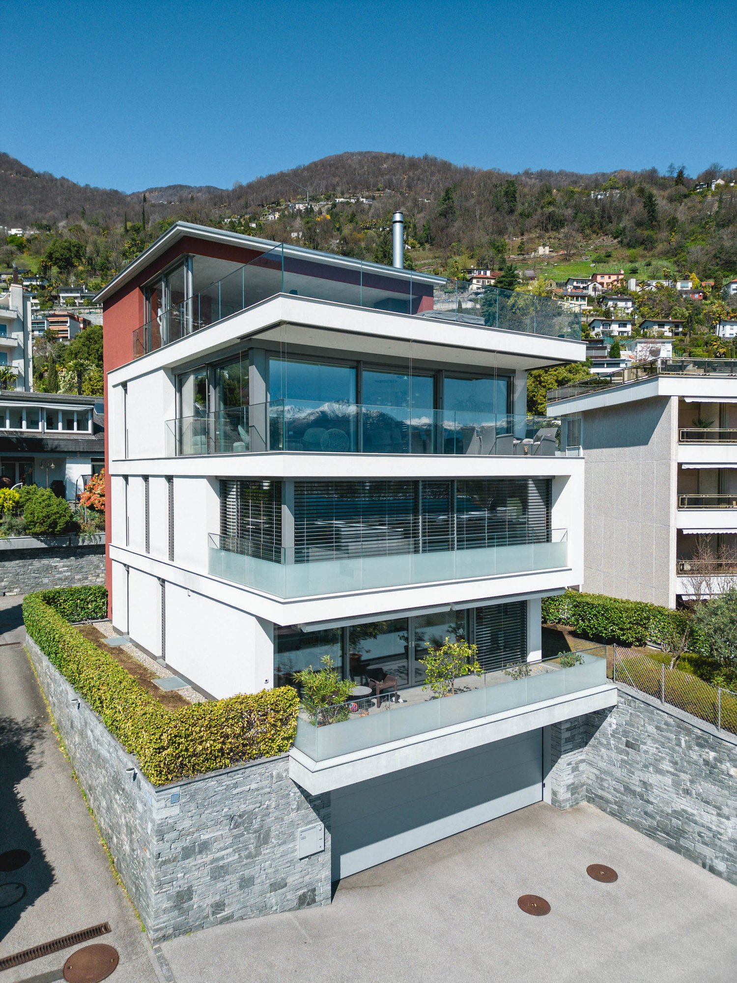 Modern 3-story house, glass facade, multiple balconies, mountain view