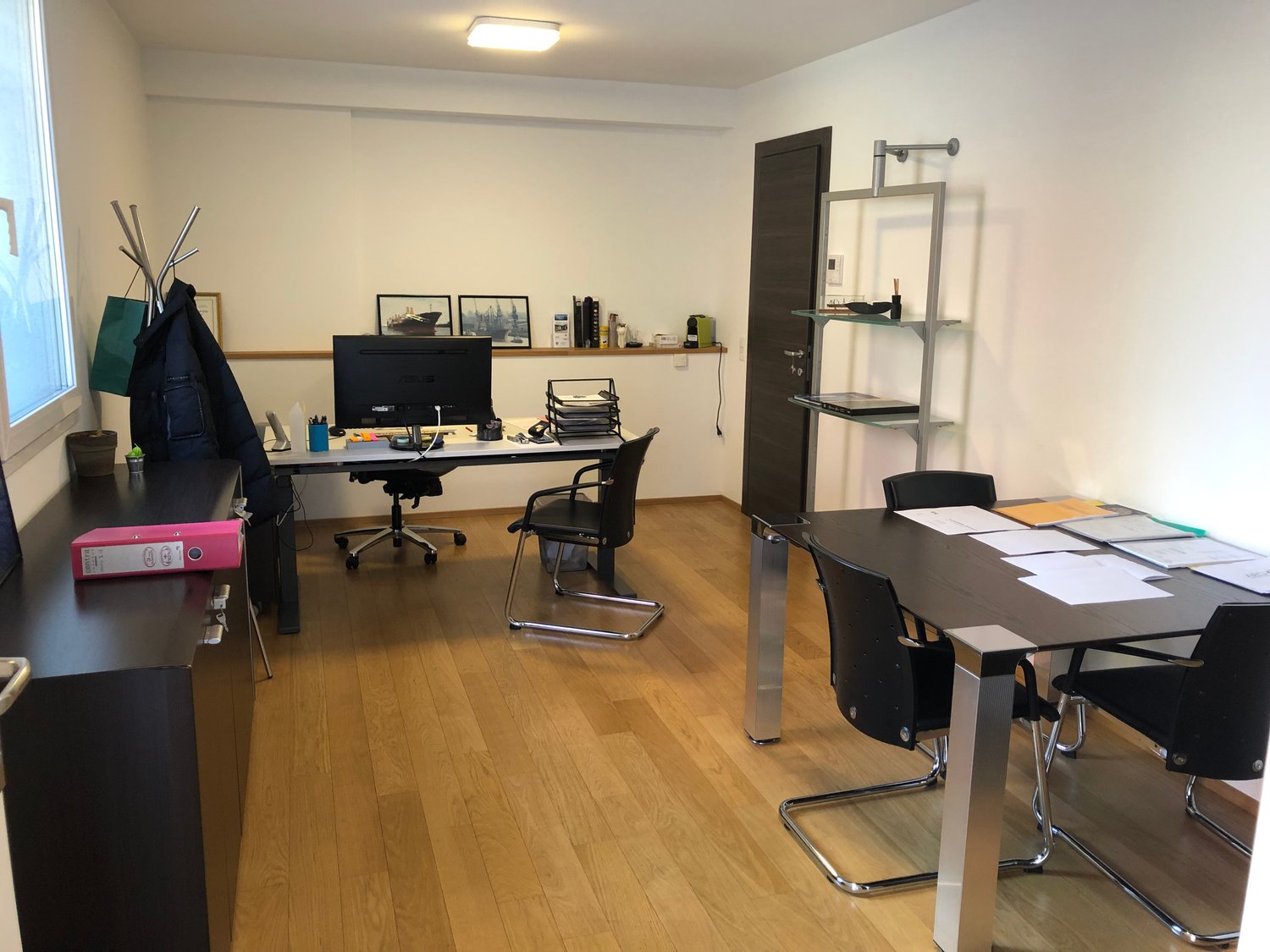modern office with desks, chairs, shelves, computer monitor, books, potted plants, windows, lamps