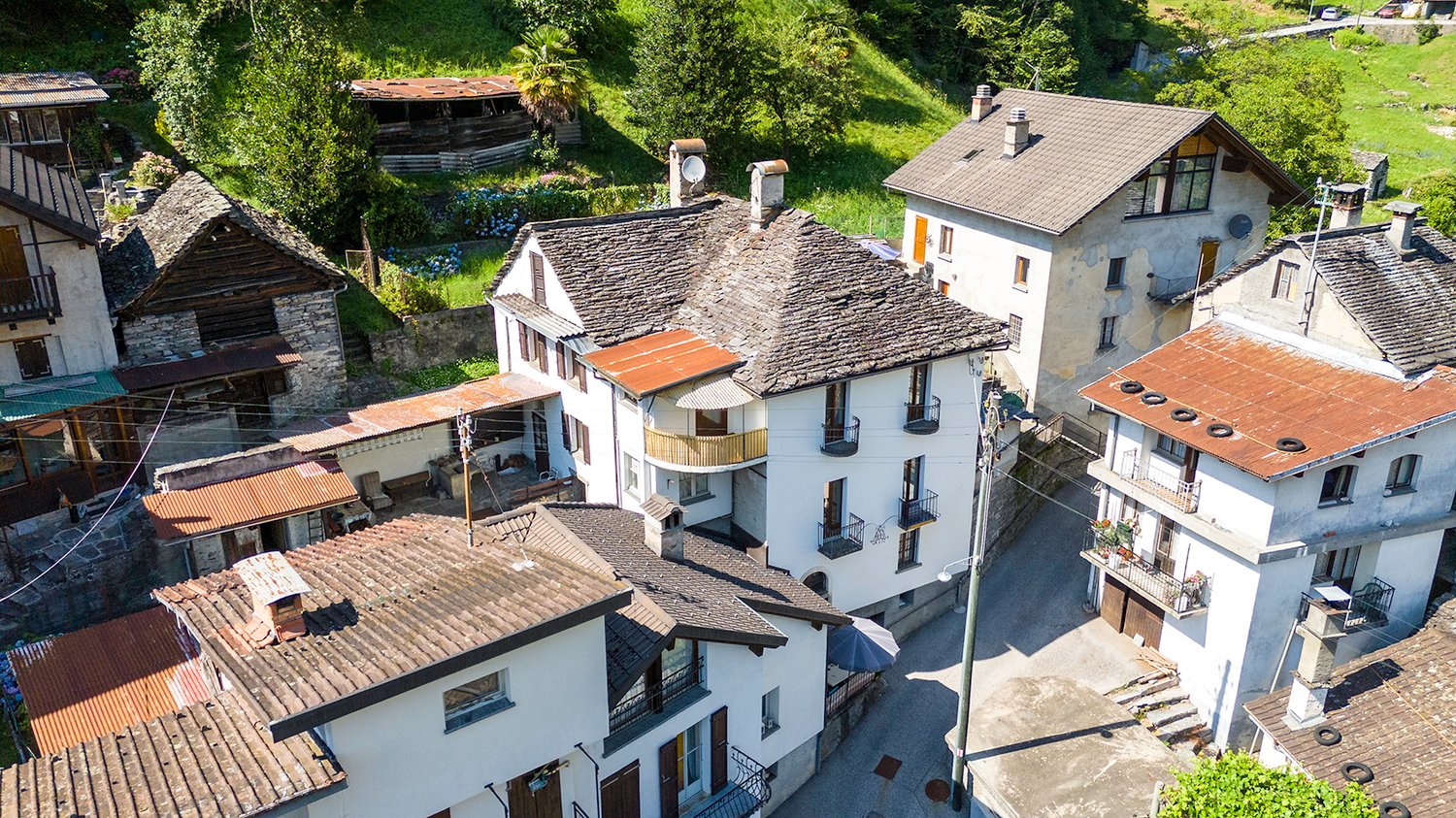 multiple houses, stone walls, roofs with tiles, balconies