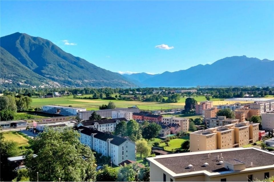 Aerial view of a town with buildings, mountains, and a lake in the distance