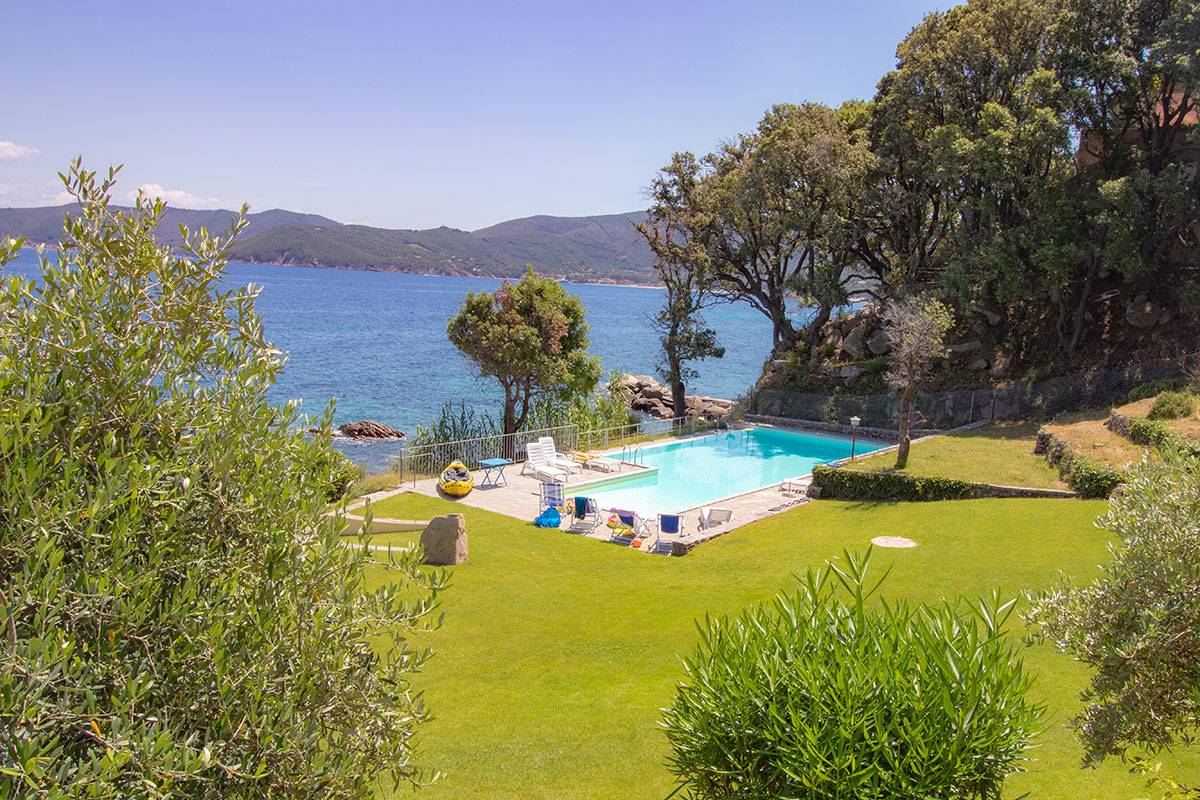 grassy lawn, swimming pool, chairs, pool side tables, view of the sea