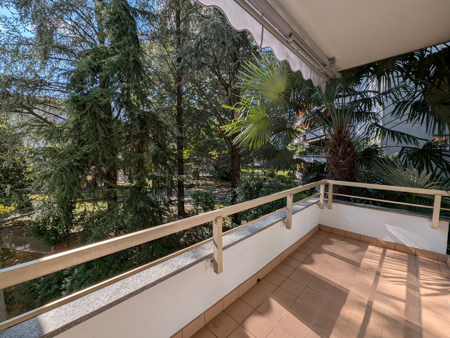 covered balcony, metal railings, tiled floor, surrounded by greenery