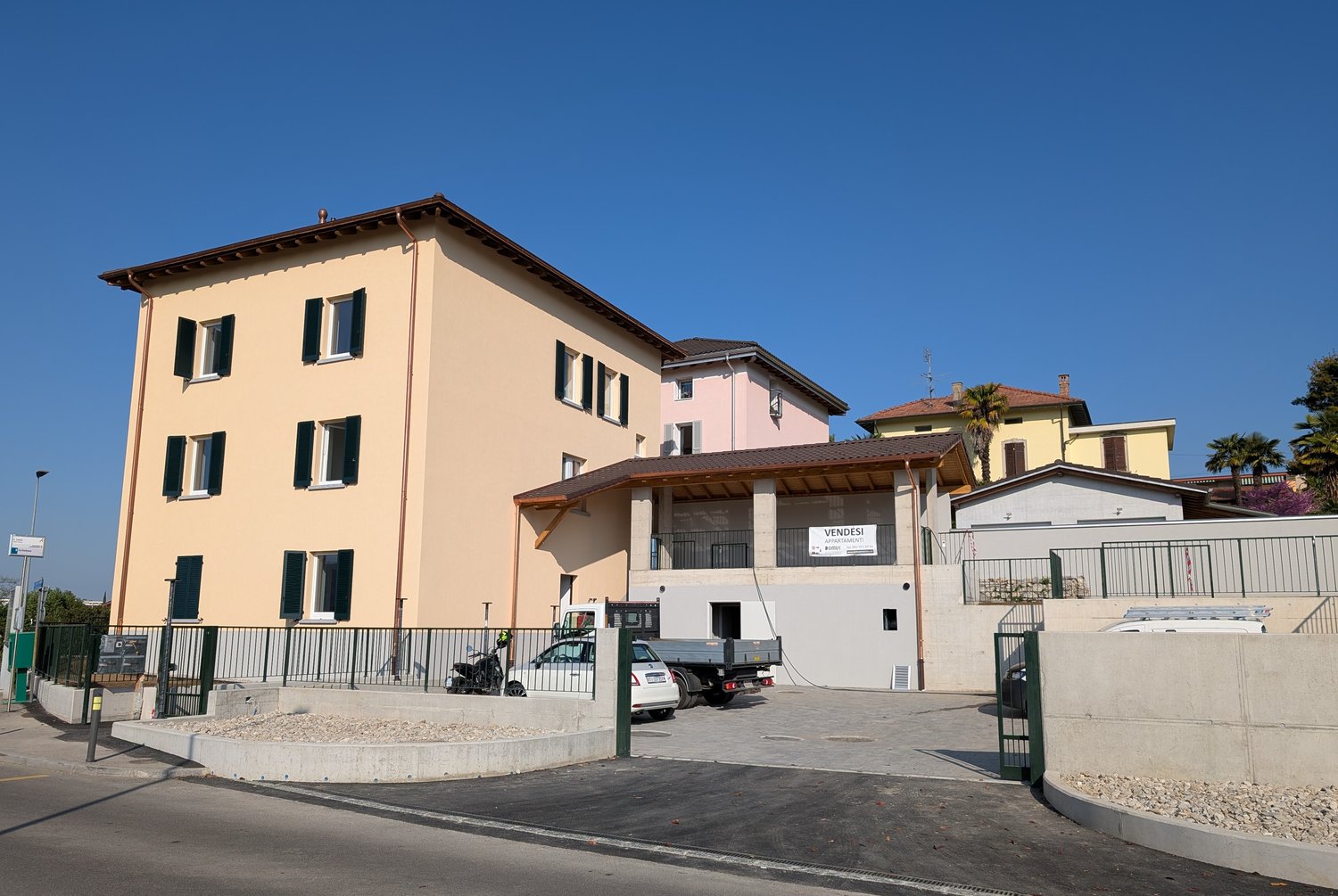 3 story building, beige exterior, multiple windows, parking lot, sign reading 'Vendesi'