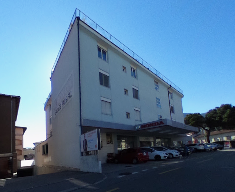 white building, multiple windows, sign reading 'Garage Parisfal', cars parked in front
