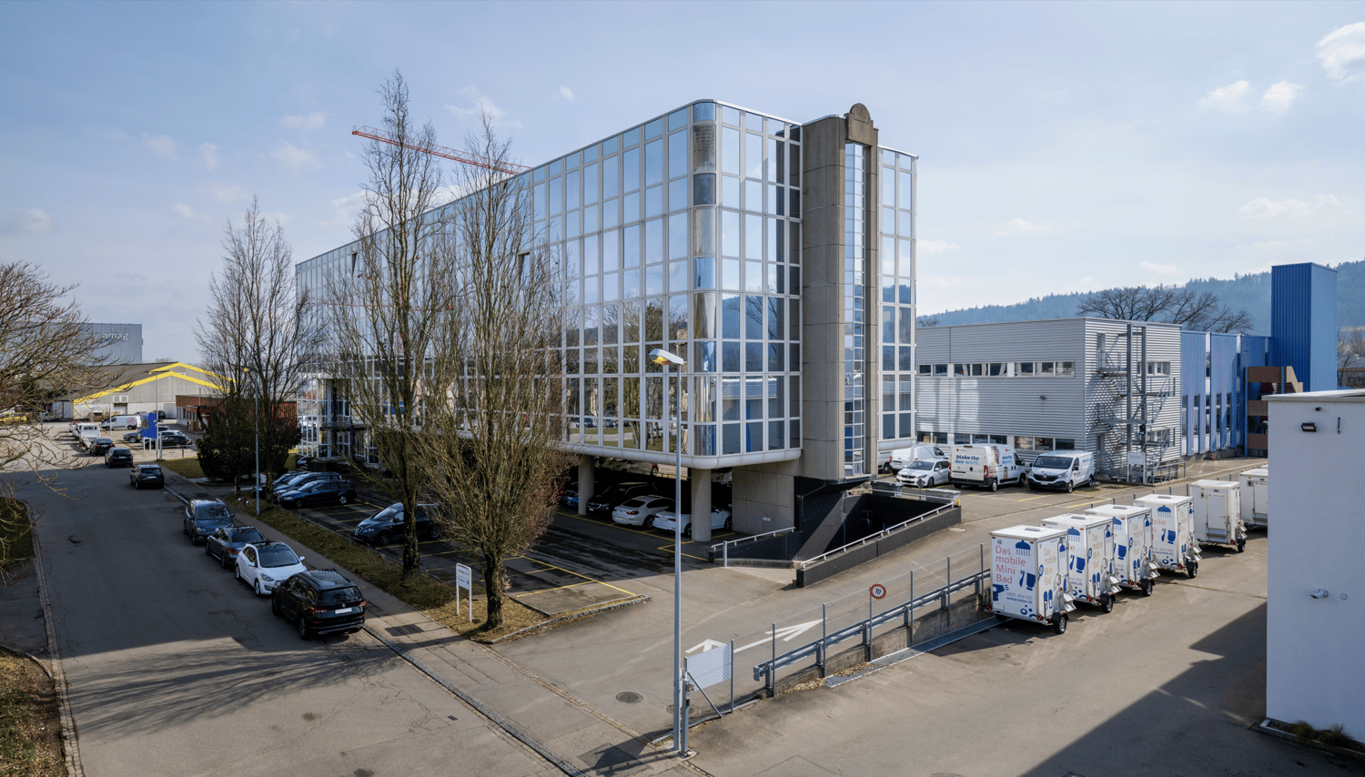modern office building, glass facade, multiple floors, parking lot, multiple vehicles