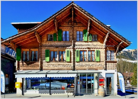 2 story wooden house, green shutters, awning, mountains in background