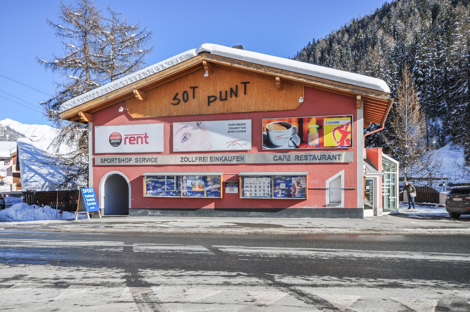 Red building with text 'SOT PLUNT', three signs for sport, perfume, and restaurant