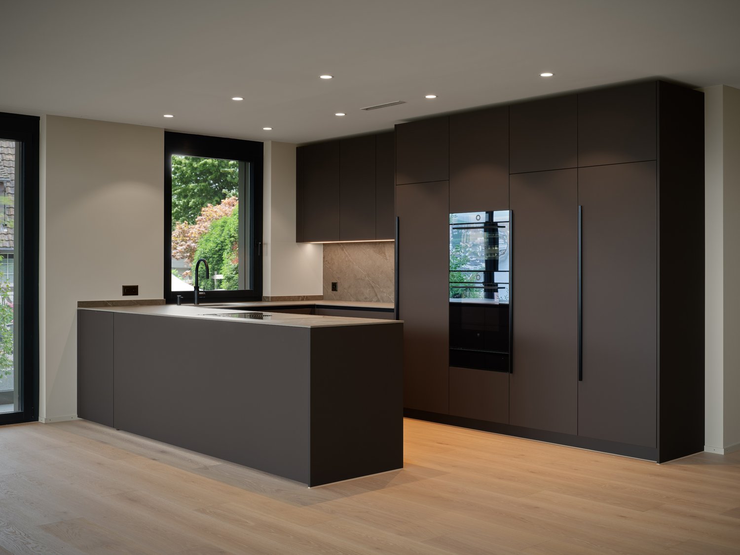 modern open-plan kitchen, grey cabinets, island with built-in stove, large windows, large kitchen appliances