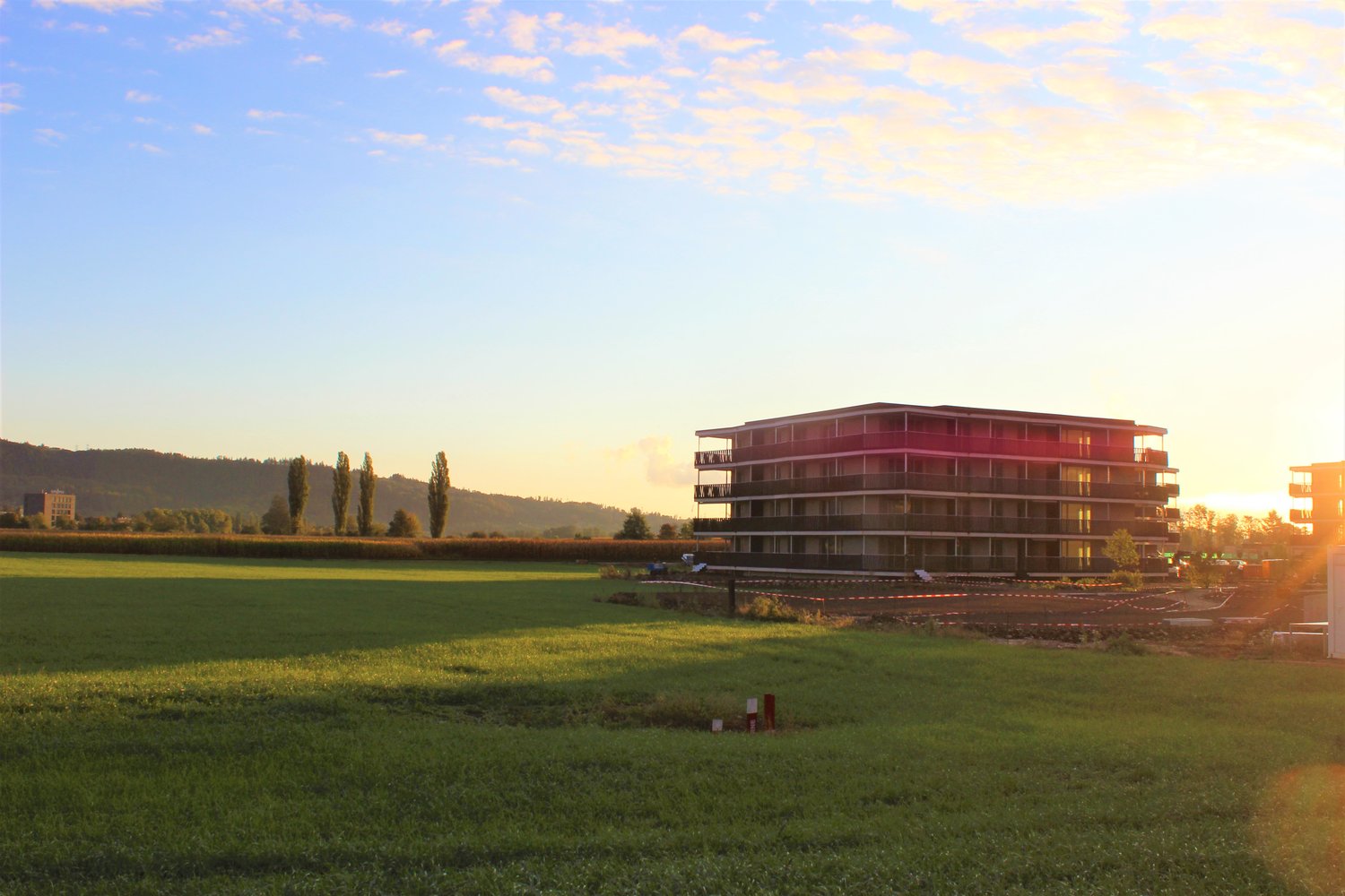 apartment building in a large green field with a view of the mountains