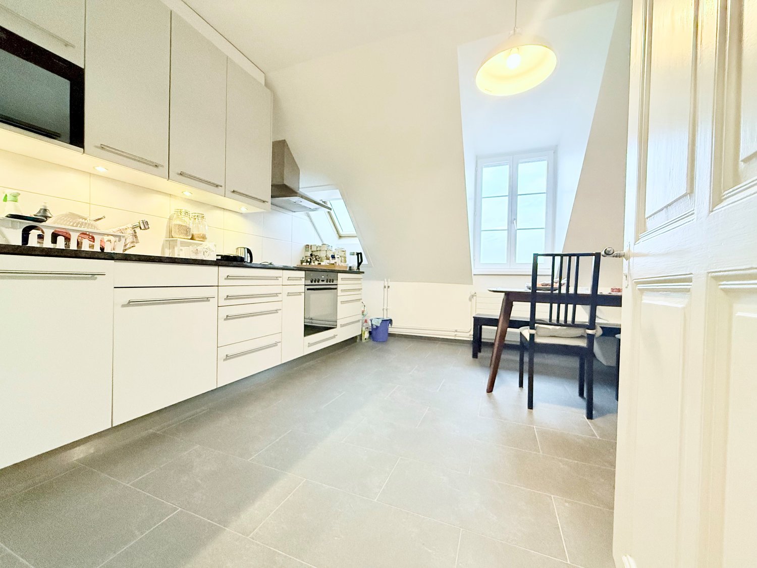 modern kitchen, white cabinets, black countertops, appliances, ceiling lamp, dining table, chairs